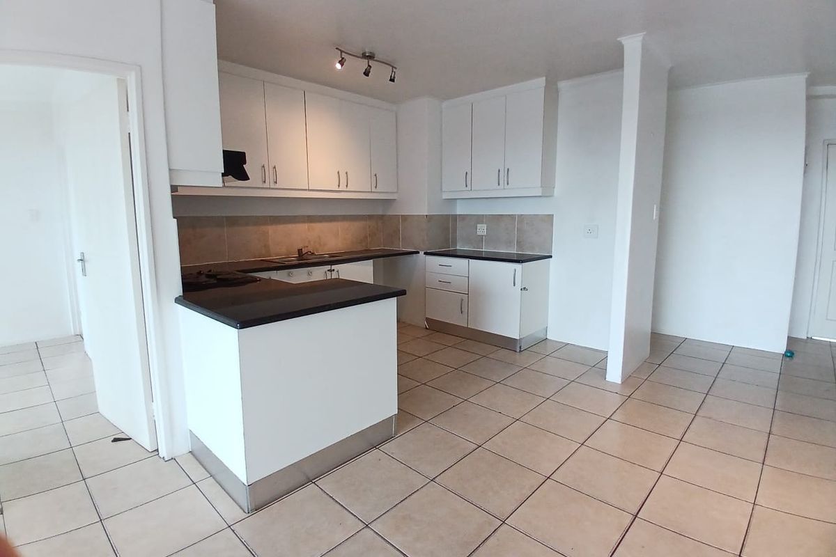 A clean, functional kitchen featuring white cabinetry, dark countertops, tiled backsplash, and ceramic flooring, offering a neutral space ready for personalization.