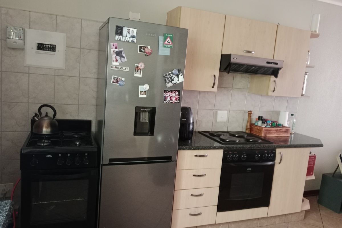 A functional kitchen featuring light wood cabinetry, granite countertops, tiled backsplash, and a combination of built-in and freestanding cooking appliances.