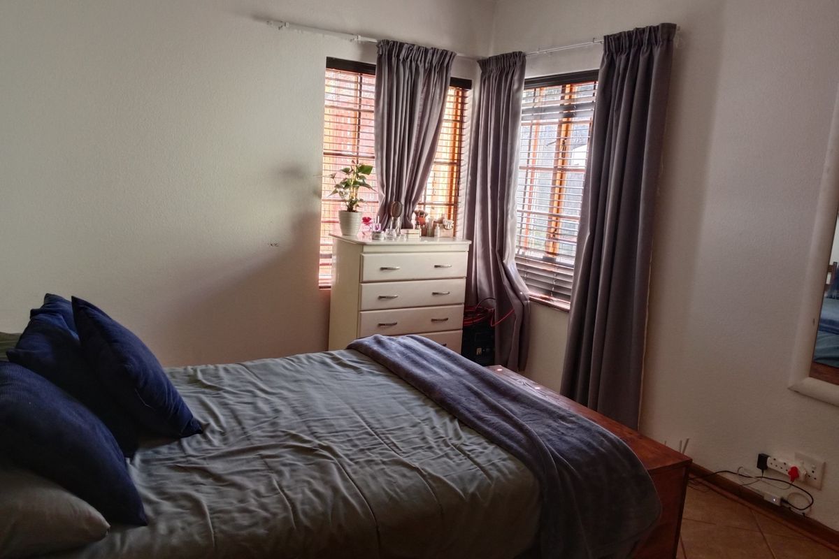 A bedroom featuring tiled flooring, dual windows with curtain tracks, and standard electrical fixtures.