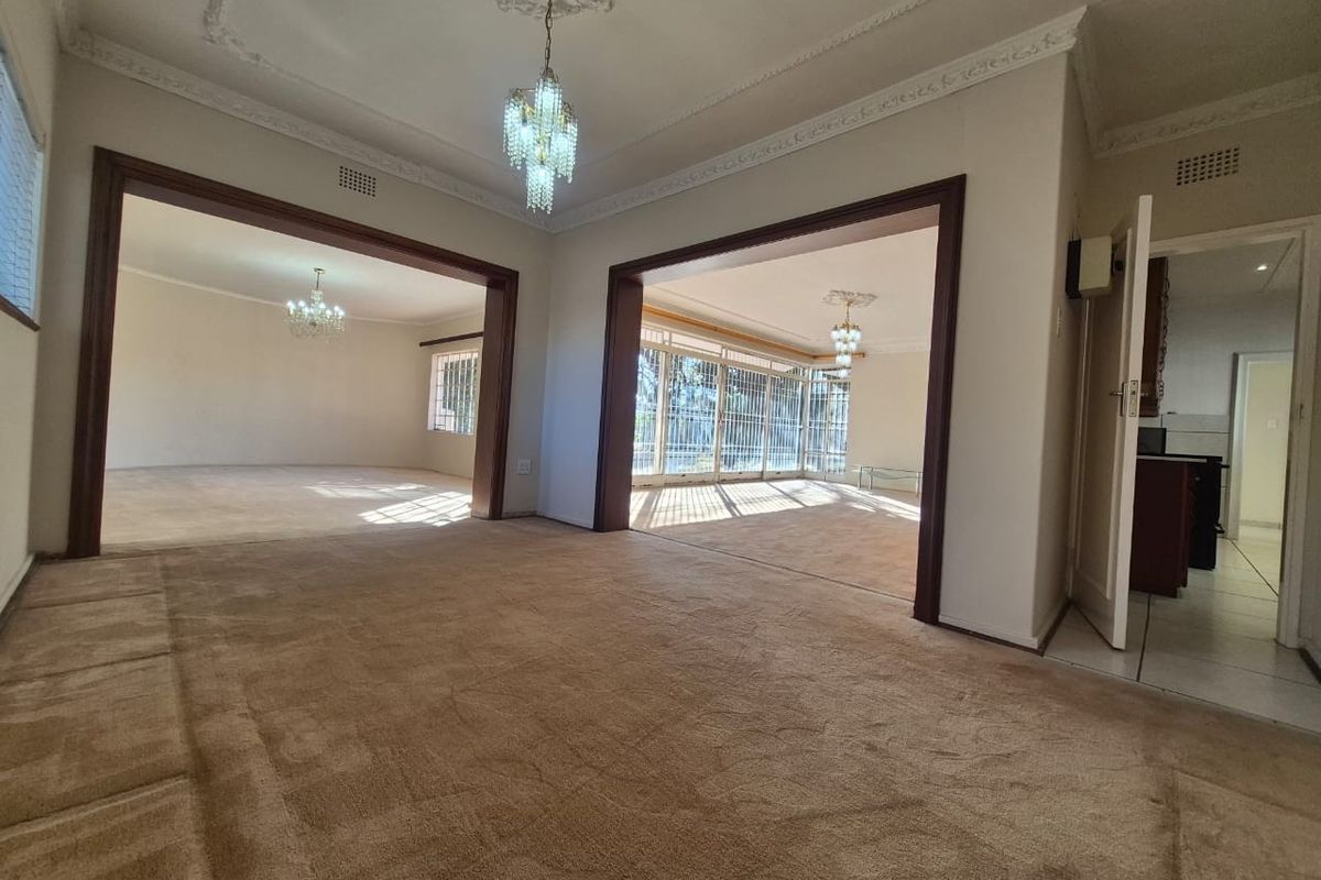 Spacious, interconnected living areas featuring ornate ceiling cornices, crystal chandeliers, and neutral carpeting, offering a versatile layout with abundant natural light.