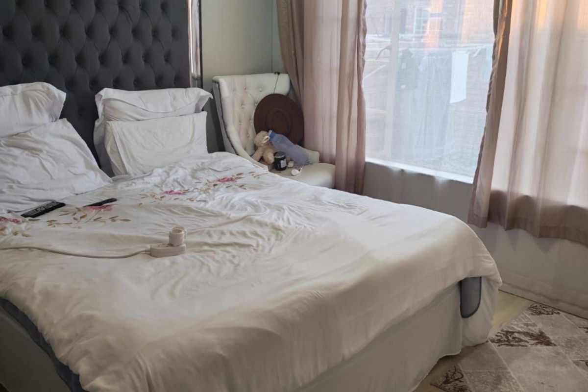 A bedroom featuring laminate flooring and decorative cove cornice, offering a functional space with natural light.
