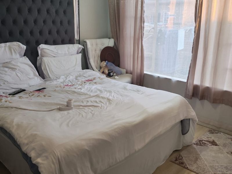 A bedroom featuring laminate flooring and decorative cove cornice, offering a functional space with natural light.