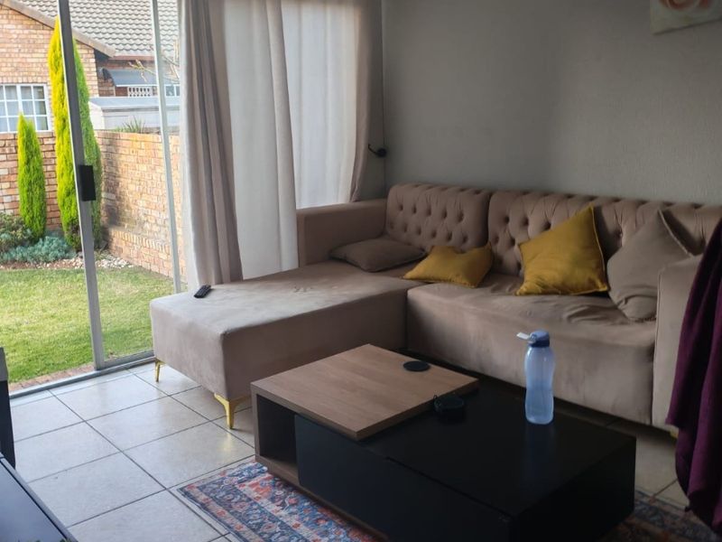 A comfortable living room featuring tiled flooring and a large sliding glass door that provides direct access to the rear garden area.