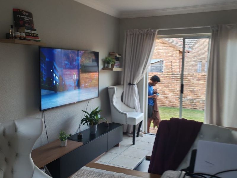 A living room featuring tiled flooring and a sliding glass door providing access to the rear garden area.