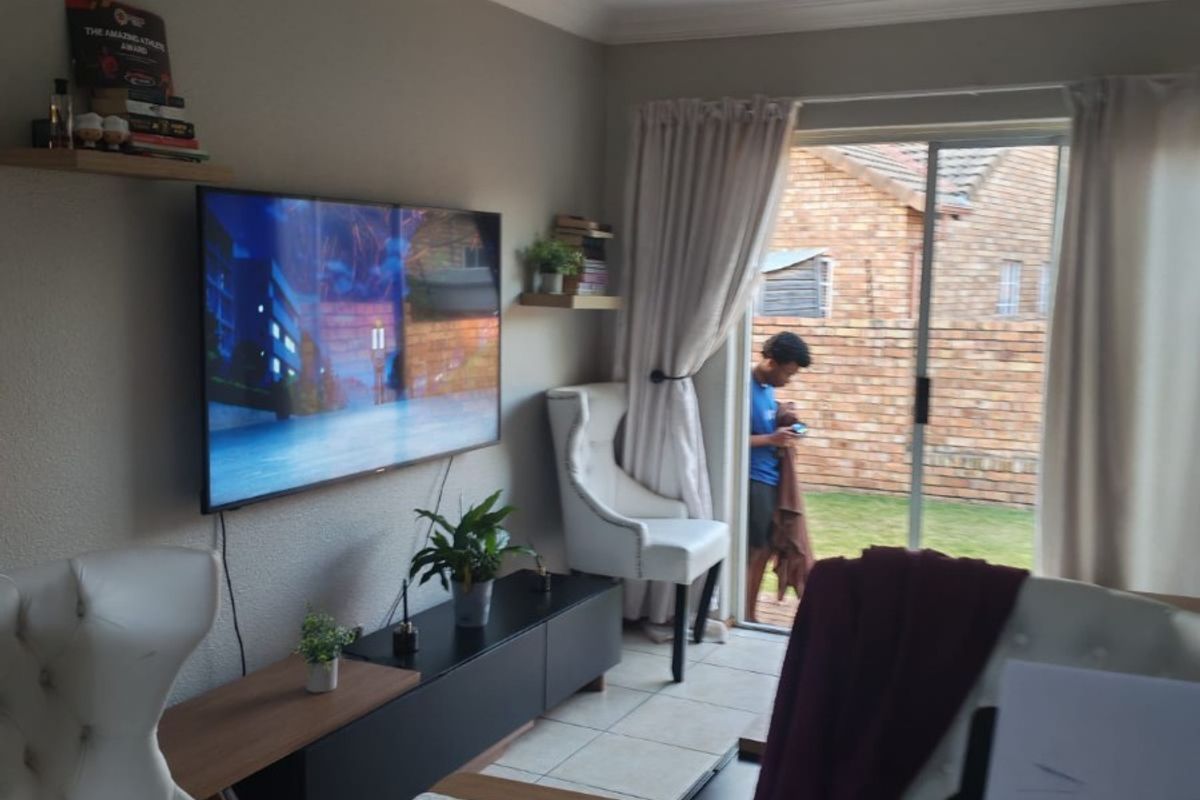 A living room featuring tiled flooring and a sliding glass door providing access to the rear garden area.