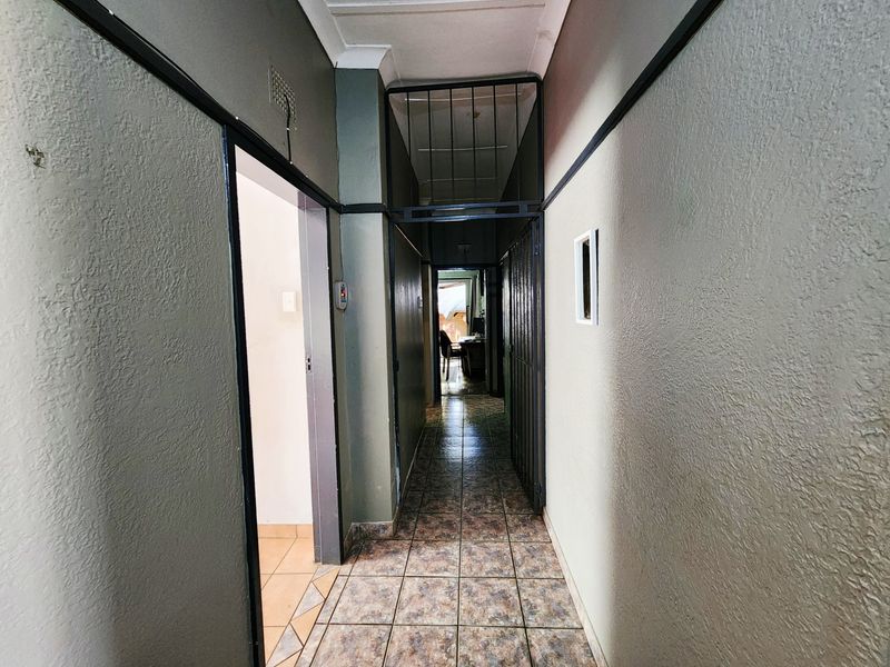 A functional hallway featuring tiled flooring and a security gate, providing access to adjacent rooms within the property.