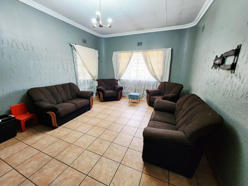 A living room featuring ceramic tile flooring, textured walls, and decorative ceiling cornicing, providing a functional space for relaxation.