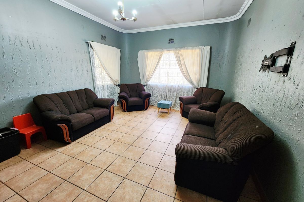 A living room featuring ceramic tile flooring, textured walls, and decorative ceiling cornicing, providing a functional space for relaxation.
