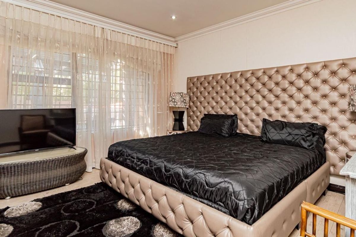 Spacious bedroom featuring crown molding, recessed downlighting, and a large sliding glass door with security bars providing access to the exterior.
