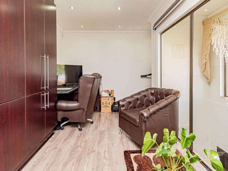 A functional home office featuring built-in dark wood cabinetry, recessed lighting, and sliding glass doors providing natural light and access to the exterior.
