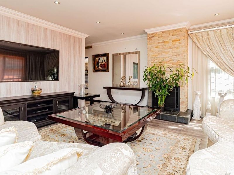 Spacious living room featuring a stone-clad fireplace, recessed downlighting, crown molding, and durable laminate flooring, creating a warm and inviting atmosphere.