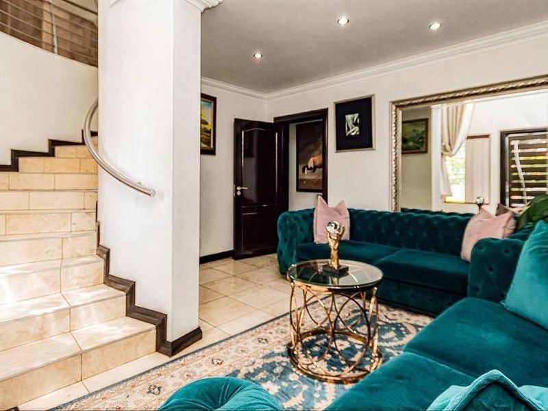 A well-maintained living area featuring tiled flooring, recessed lighting, and a staircase with a modern stainless steel handrail.