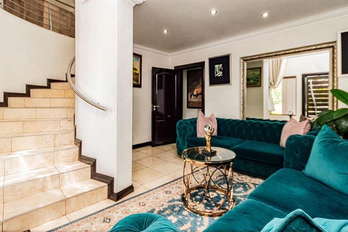 A well-maintained living area featuring tiled flooring, recessed lighting, and a staircase with a modern stainless steel handrail.