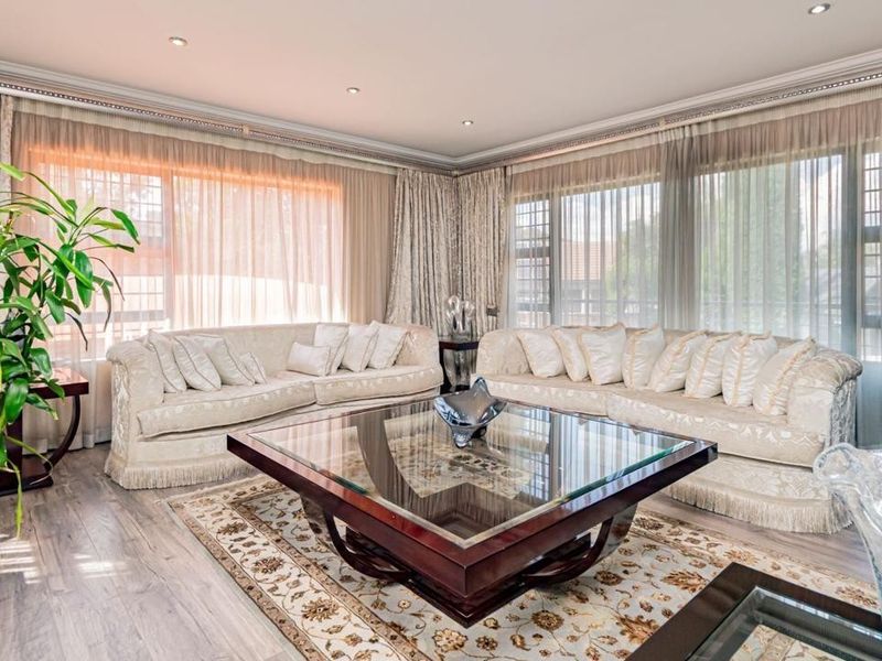 A bright and spacious living room featuring laminate flooring, recessed downlighting, decorative cornicing, and large windows that allow for ample natural light.