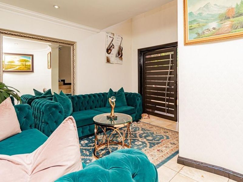 A well-maintained living room featuring tiled flooring, recessed downlighting, decorative coving, and a modern security front door.