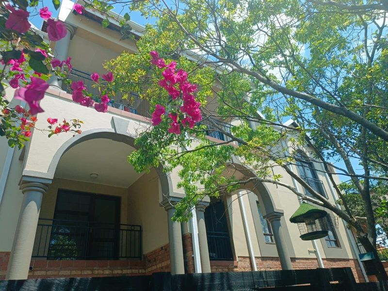 A view of the apartment building facade featuring arched architectural details, balconies with wrought iron railings, and a brick base.