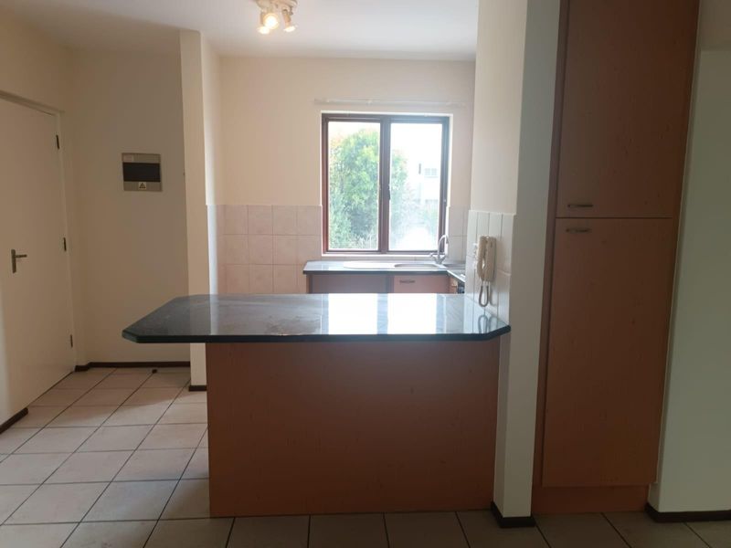 A functional kitchen area featuring a granite breakfast bar, built-in cabinetry, and tiled flooring, offering a clean and neutral space ready for updates.