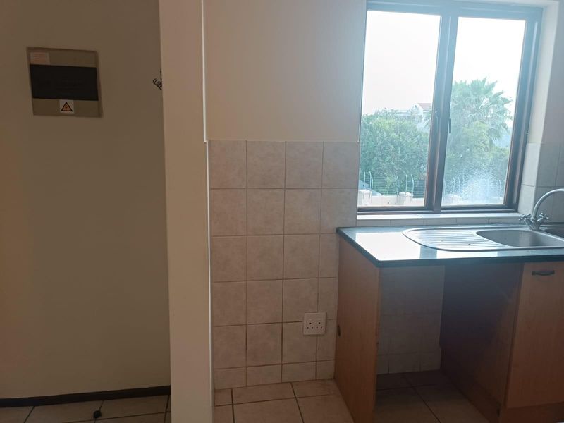 A functional kitchen area featuring a sink, tiled splashback, and base cabinetry, providing a practical space for culinary tasks.