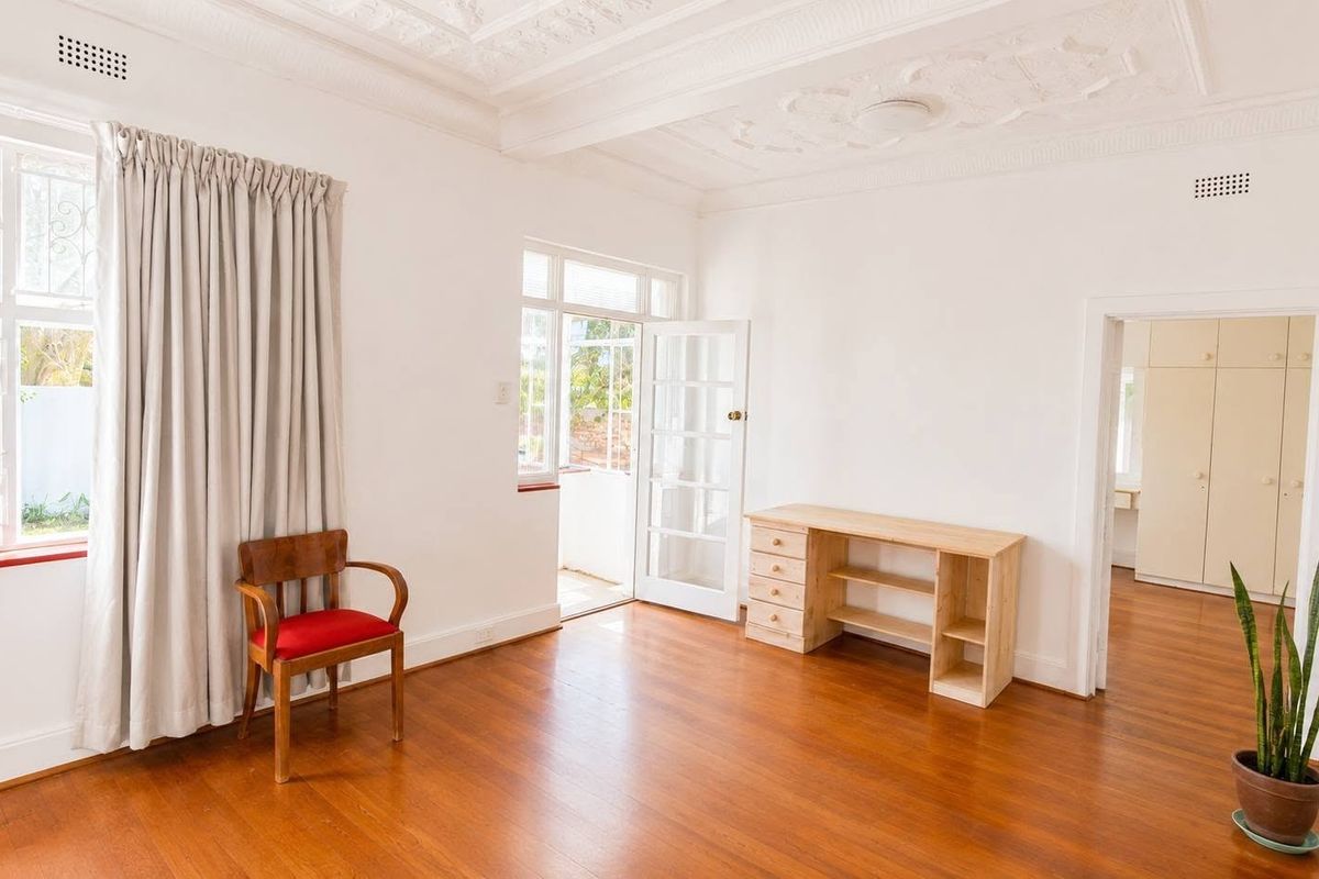 Spacious bedroom featuring polished hardwood floors, an ornate plaster ceiling, and direct access to an outdoor area through classic french doors.
