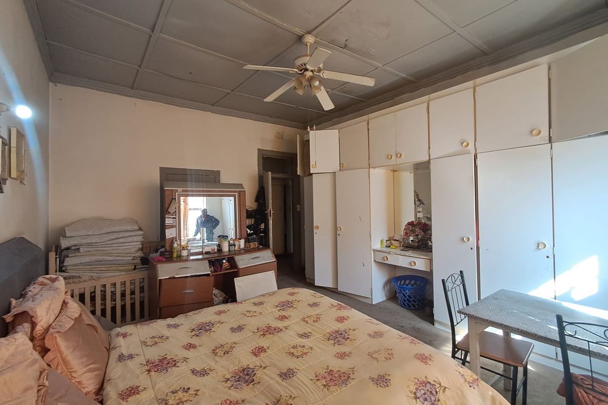 Bedroom featuring extensive built-in cabinetry, a ceiling fan, and a tiled ceiling. The room shows signs of age and requires cosmetic updates.