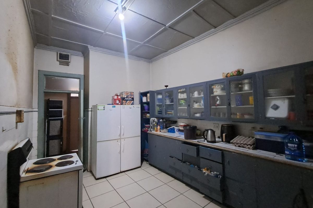 A dated kitchen featuring built-in cabinetry, tiled flooring, and an electric stove, requiring cosmetic updates to improve its overall condition and appeal.