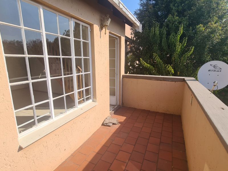 A private balcony featuring terracotta tile flooring, plastered walls, and a multi-pane window, offering an outdoor space for relaxation.