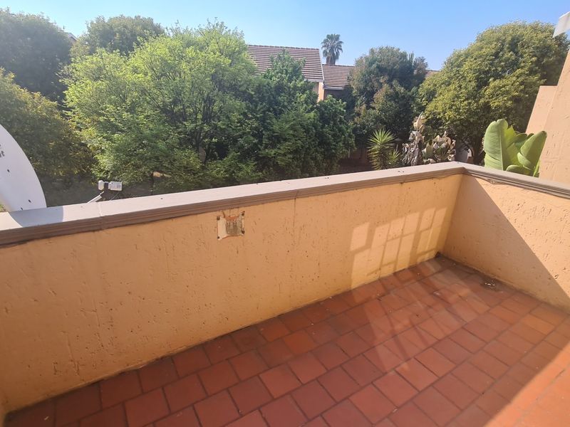 A private balcony featuring tiled flooring and a parapet wall, offering an outdoor space with views of the surrounding greenery.
