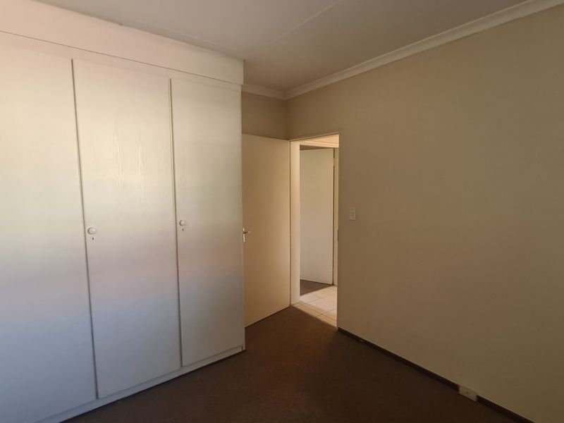 A clean, empty bedroom featuring built-in cupboards and neutral wall finishes, offering a versatile space ready for personalization.