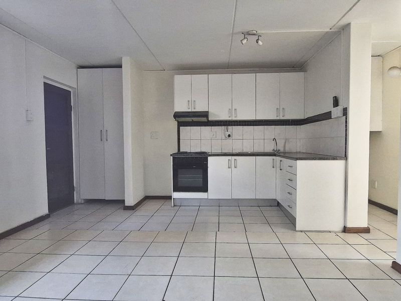Open plan kitchen and living area featuring tiled flooring, built-in cabinetry, and an integrated oven with extractor fan.