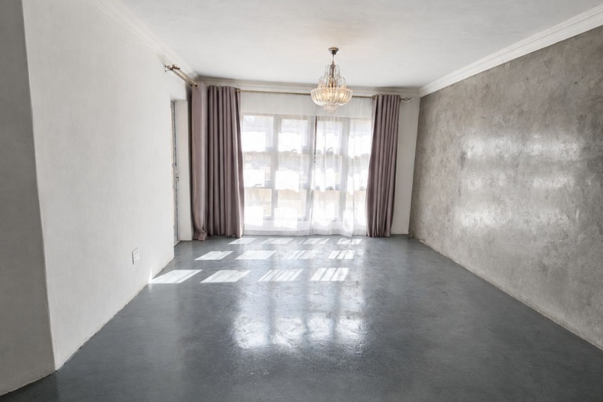 Spacious living area featuring polished concrete floors, a textured feature wall, and decorative cornice, offering a clean and modern blank canvas.