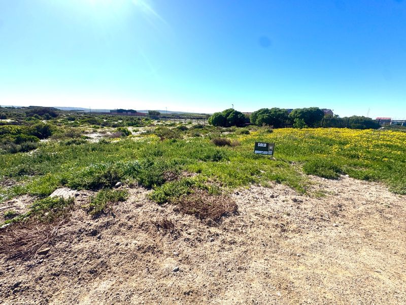 A vacant residential plot featuring natural vegetation and a sold sign, offering a clear space for future development.