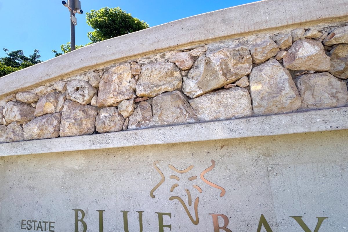 A close-up view of the Blue Bay estate entrance wall featuring decorative stone cladding and integrated security infrastructure.