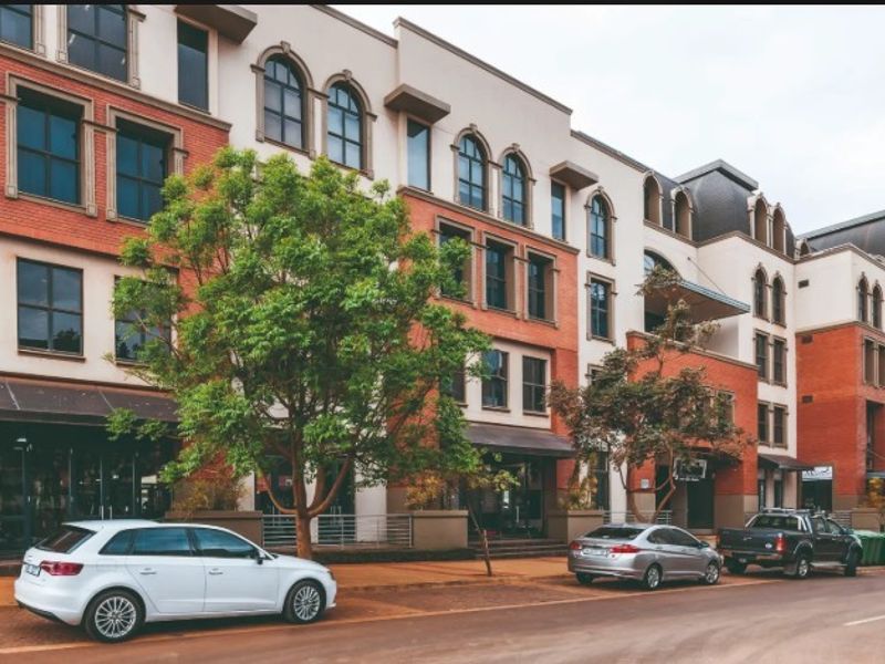 A multi-story commercial office building featuring a classic brick and stucco facade with arched windows and street-level access.