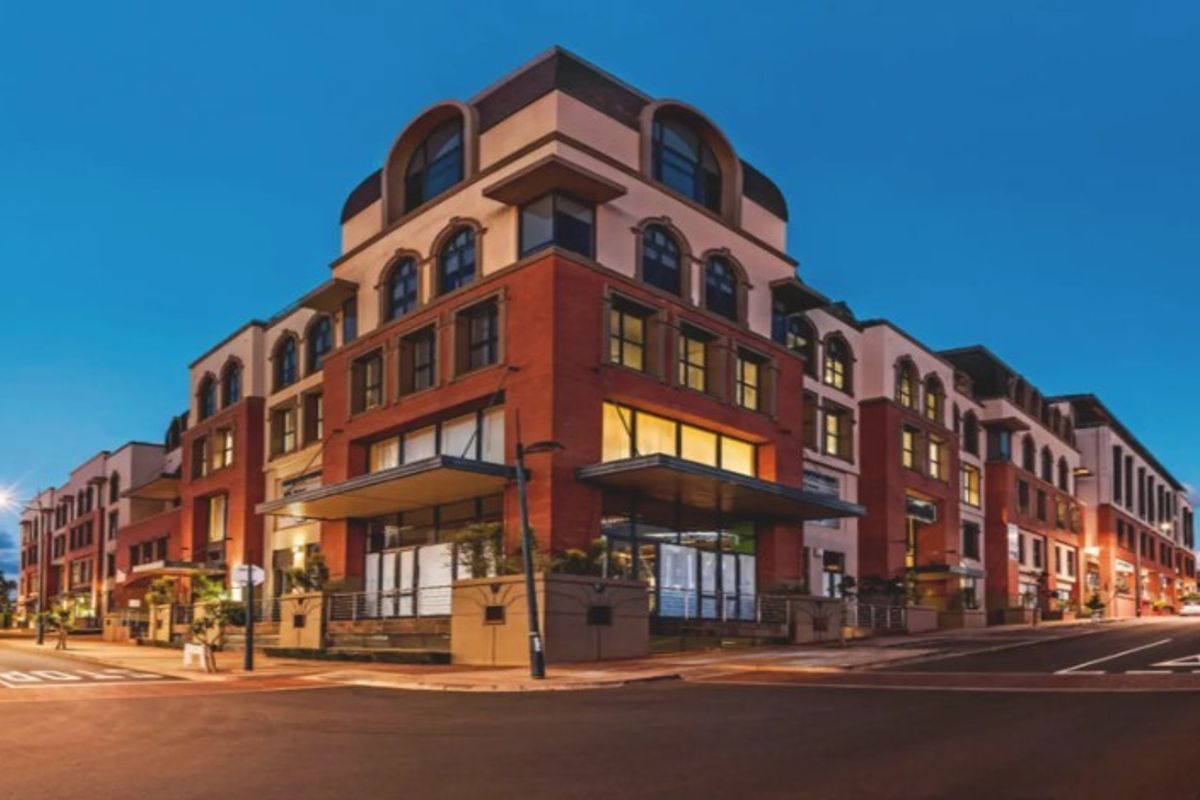 A professional exterior view of a multi-story brick office building at dusk, featuring arched windows and a prominent street-level entrance canopy.