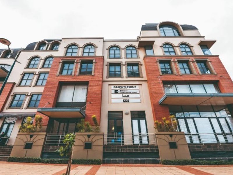 A multi-story commercial office building featuring a brick facade, arched windows, and prominent signage at the entrance.