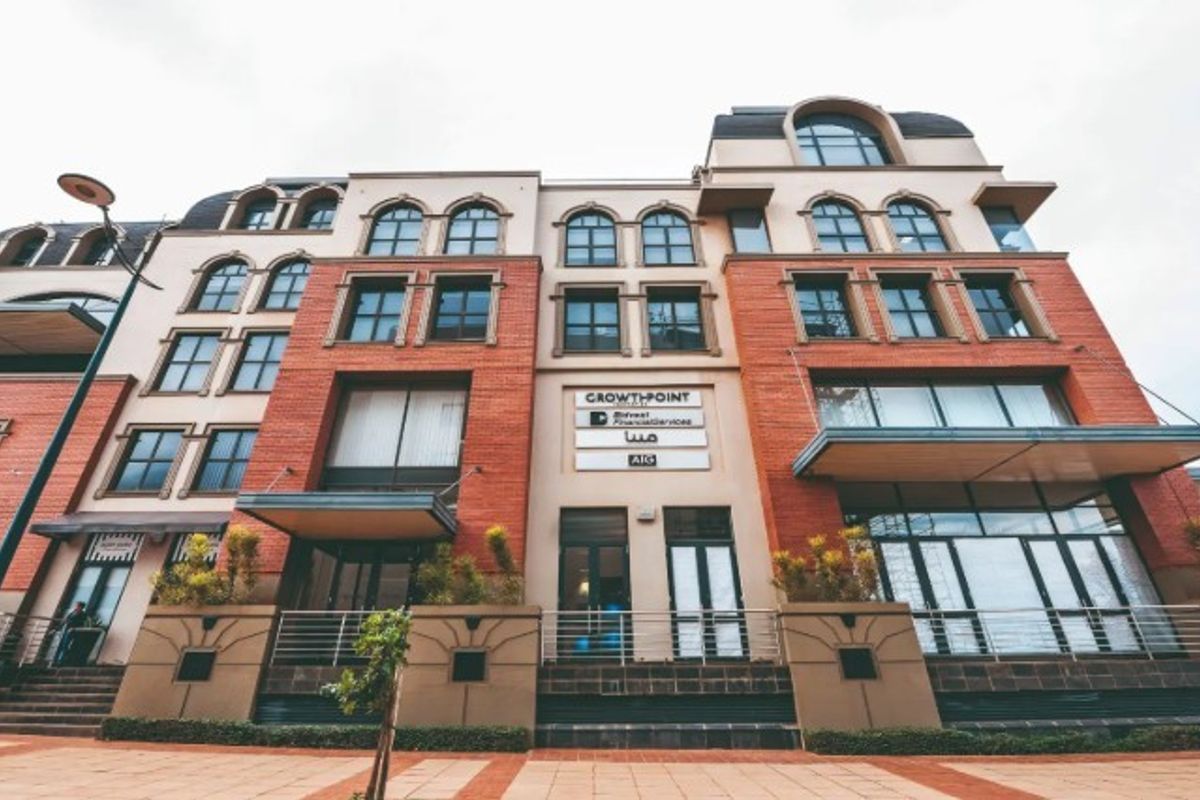 A multi-story commercial office building featuring a brick facade, arched windows, and prominent signage at the entrance.