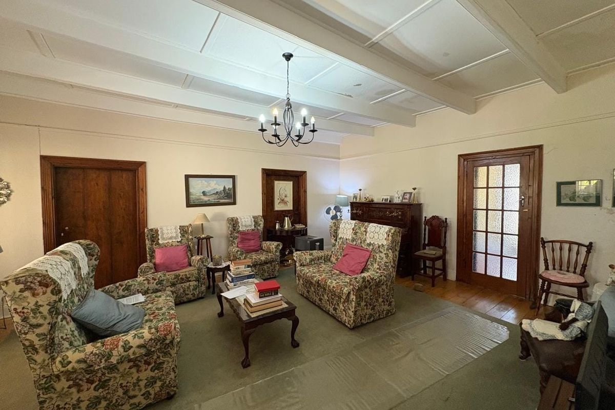 Spacious living room featuring exposed beam ceilings, traditional timber door frames, and a classic glass-panelled door, offering a warm and character-filled atmosphere.