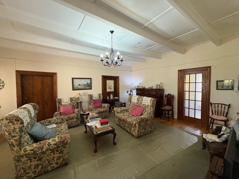 Spacious living room featuring exposed beam ceilings, traditional timber door frames, and a classic glass-panelled door, offering a warm and character-filled atmosphere.