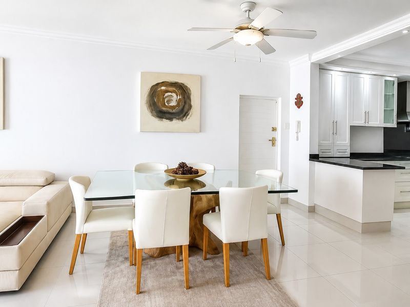 Bright open-plan living and dining area featuring tiled floors, a ceiling fan, and a modern kitchen with granite countertops and built-in appliances.