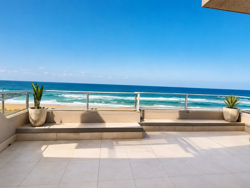 Spacious balcony featuring tiled flooring, built-in bench seating, and a glass balustrade, offering expansive, unobstructed views of the ocean and beach.