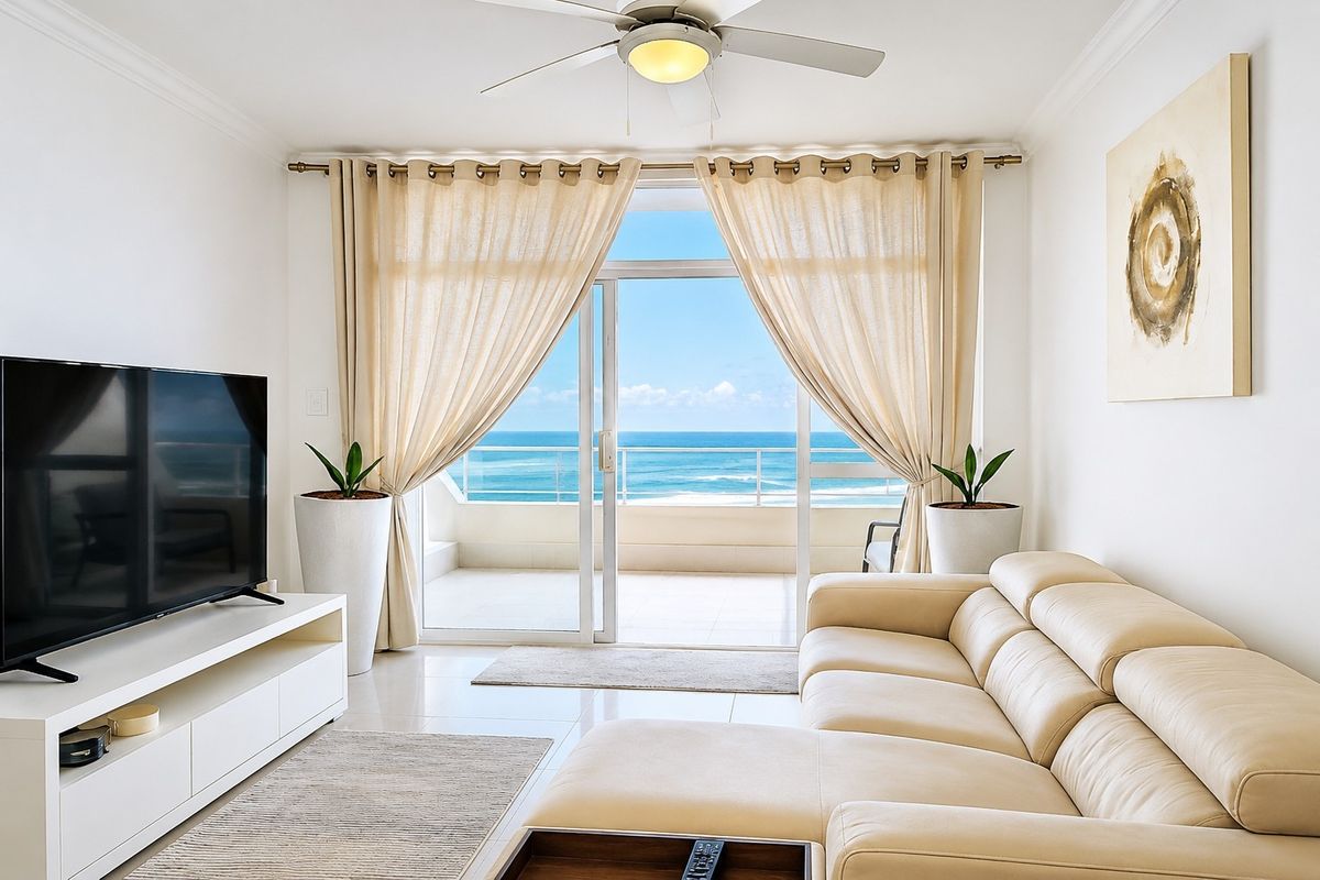 Bright living room featuring tiled floors, a ceiling fan, and large sliding glass doors opening onto a balcony with expansive ocean views.