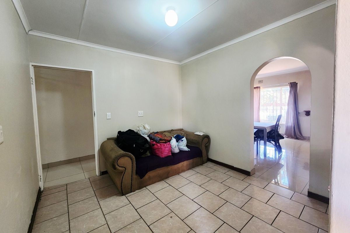 A living area featuring ceramic floor tiles, a coved ceiling, and an arched doorway leading to an adjacent room.