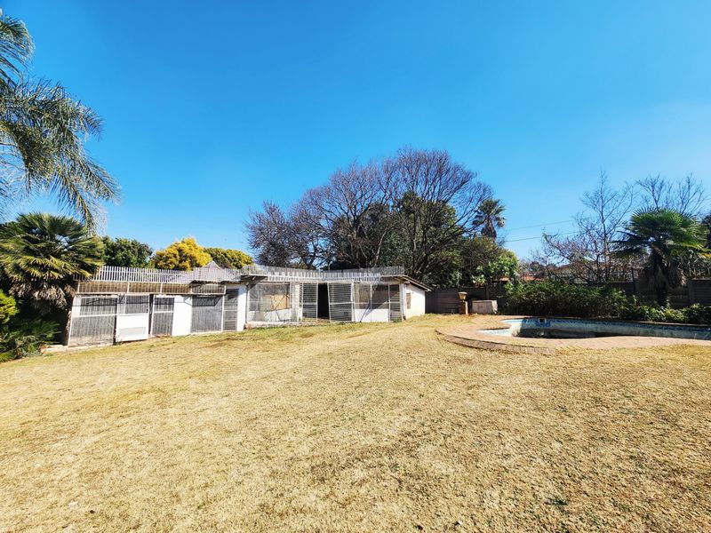 Rear garden area featuring a swimming pool, dry lawn, and a large fenced outdoor structure.