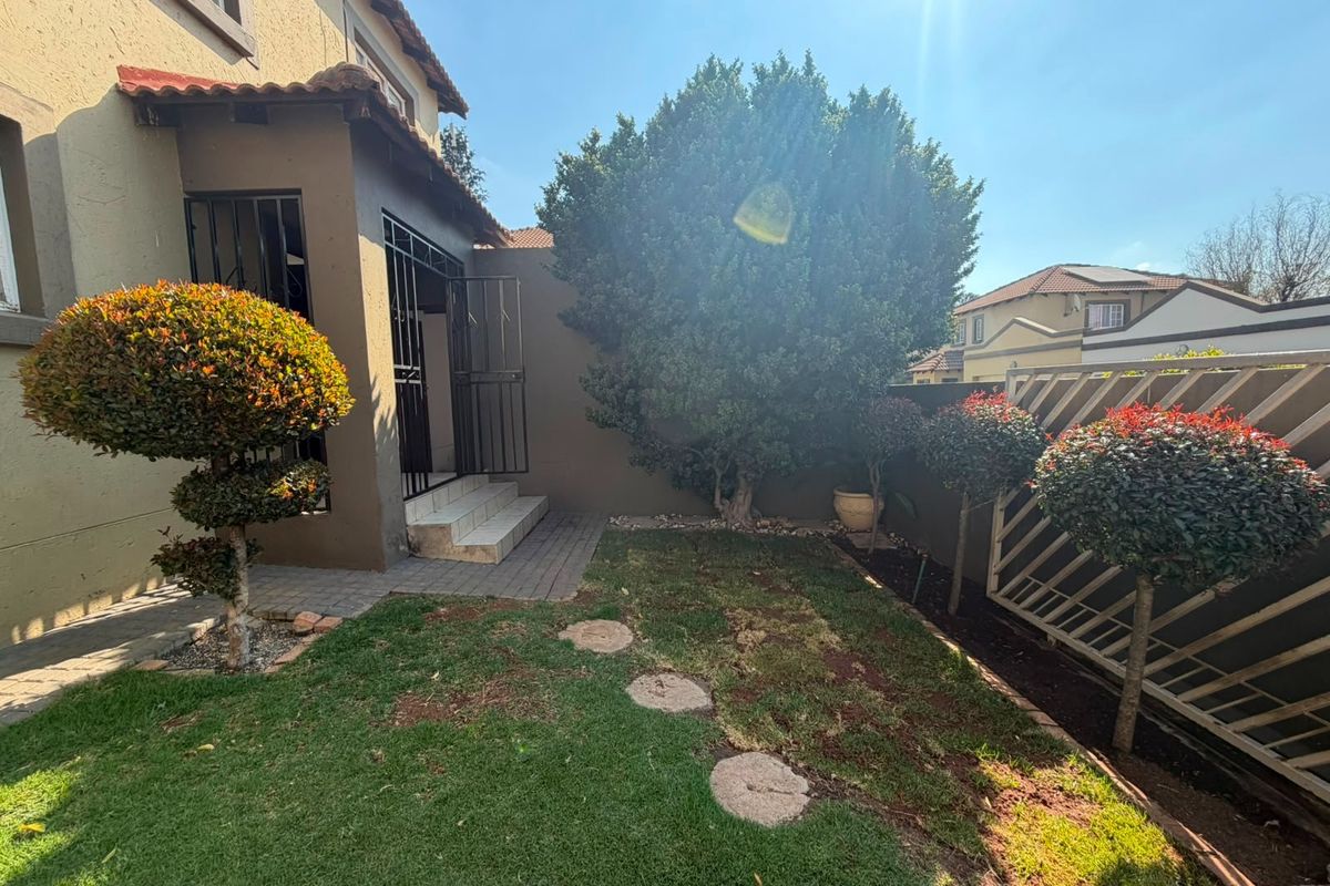 A private rear garden area featuring a paved walkway, security gate access to the home, and established boundary walling.