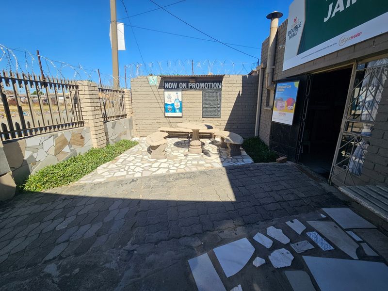Outdoor paved patio area featuring a brick boundary wall with security razor wire and stone cladding accents.
