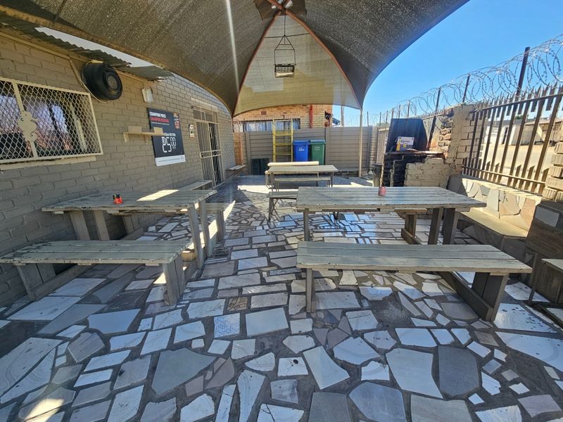 Outdoor patio area featuring crazy paving, a shade sail, and secure perimeter fencing with razor wire.