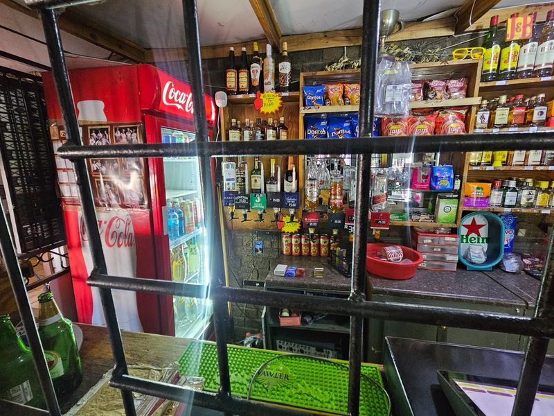A functional bar area featuring fixed shelving and a secure service counter, suitable for entertainment or hospitality use.