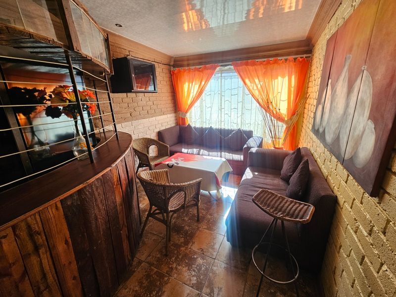 A cozy living area featuring exposed brick walls, tiled flooring, and a built-in bar counter, offering a rustic and character-filled space.