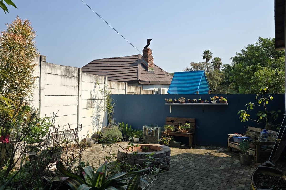 A private rear courtyard featuring a paved patio area, a built-in fire pit, and a painted feature wall, offering a functional outdoor space.