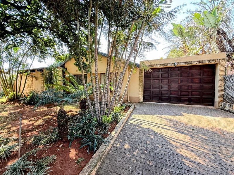 Front exterior view of the property featuring a paved driveway, double garage, and established garden landscaping.